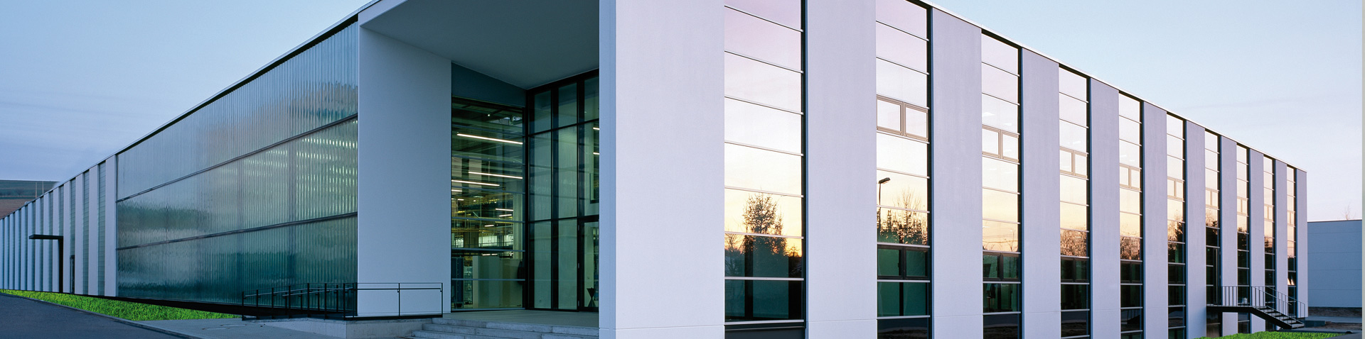Modern building with a glass and pillar facade at dusk – Hager success story
