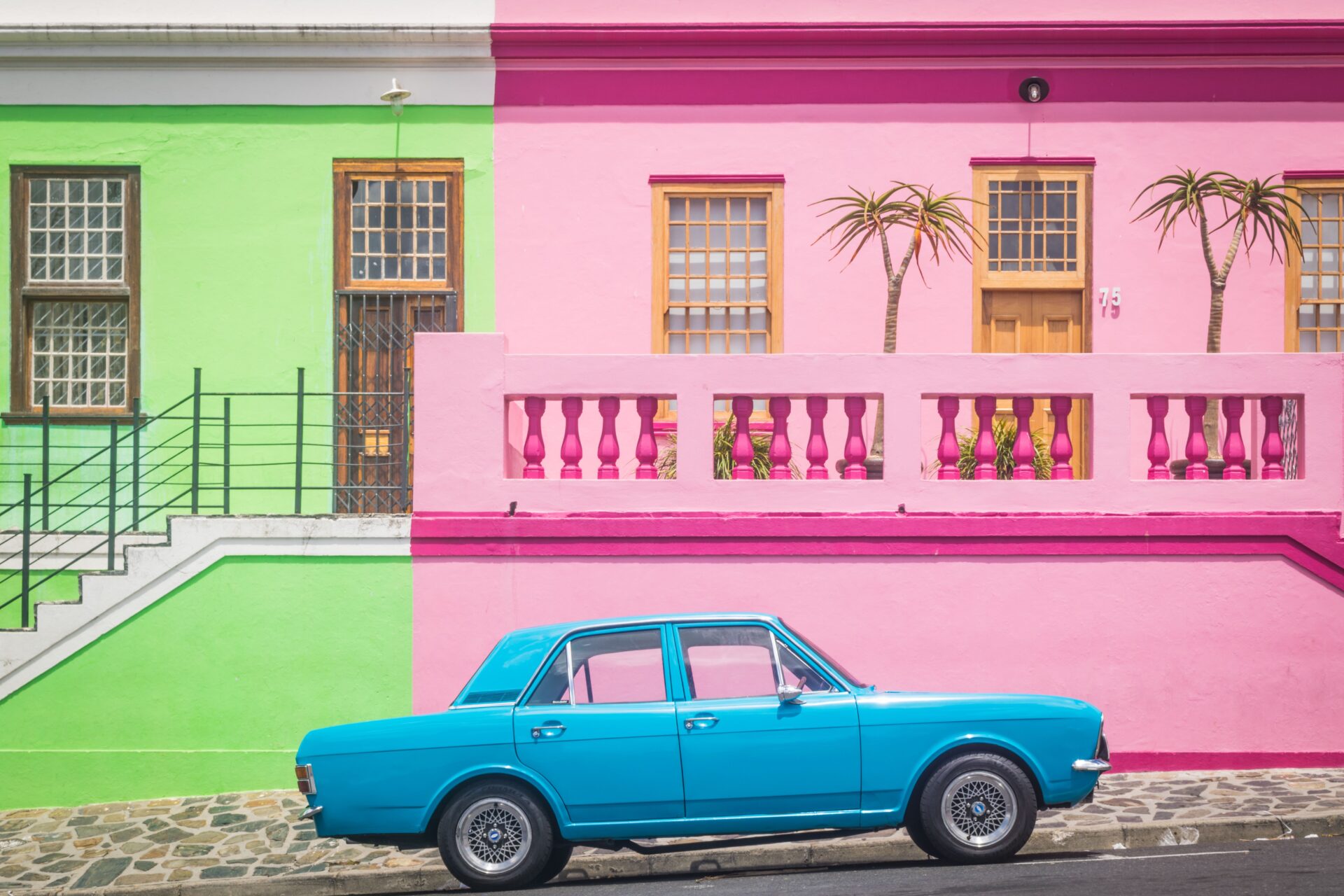 OMN ACCELERATOR - a blue car infront of a very colorful house