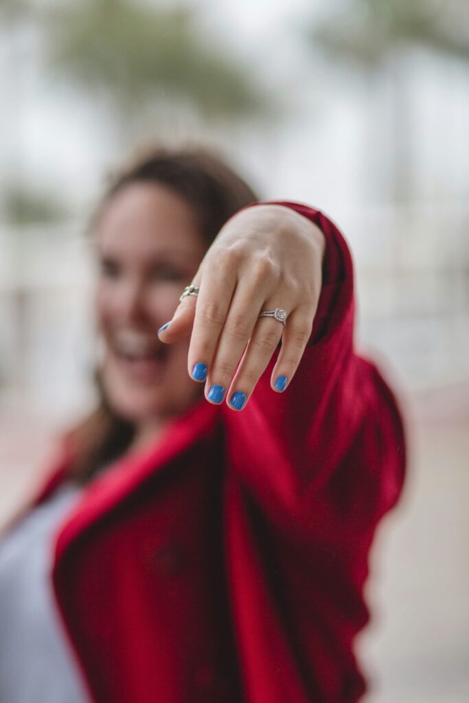 Frau im roten Mantel mit blauen Fingernägeln und einem Diamantring am Finger als Symbolbild für Blogartikel Hyperpersonalisierung