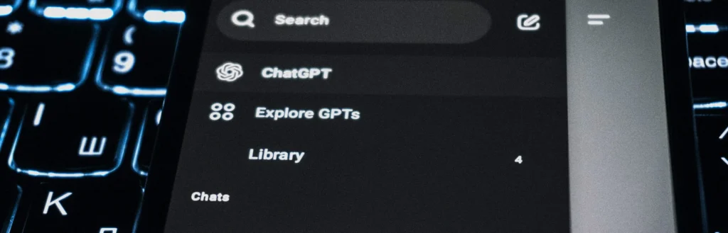 Chat-Oberfläche einer KI-Suche auf einem Smartphone über einer Laptop-Tastatur – Motiv zu GEO für Produktseiten