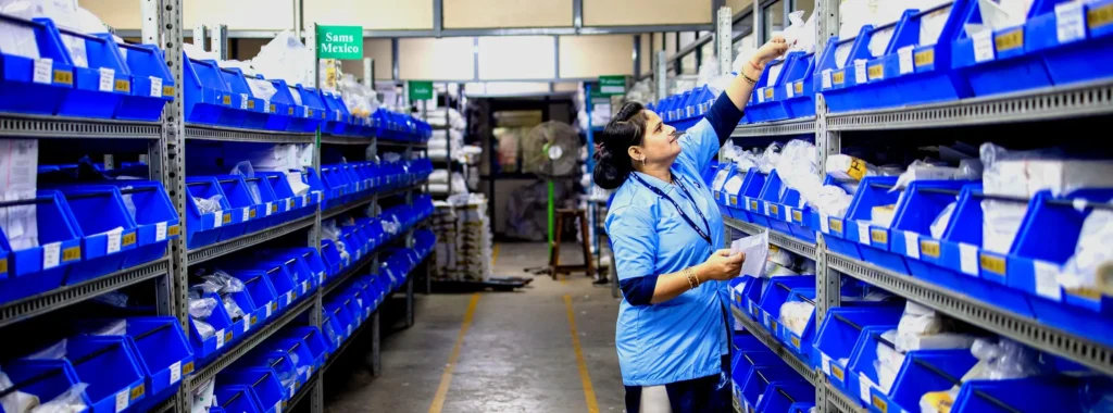 Mitarbeiterin entnimmt Kleinteile aus beschrifteten Lagerkästen – Motiv zu KI-Produktbeschreibungen aus PIM-Attributen