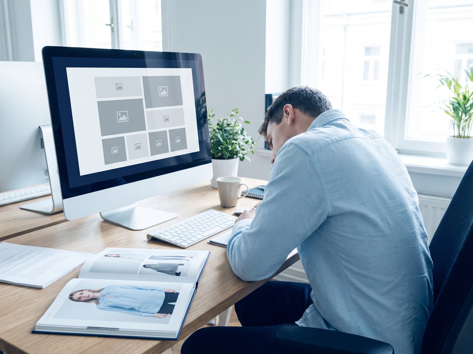 Designer arbeitet an einem Katalog-Layout, daneben der gedruckte Katalog