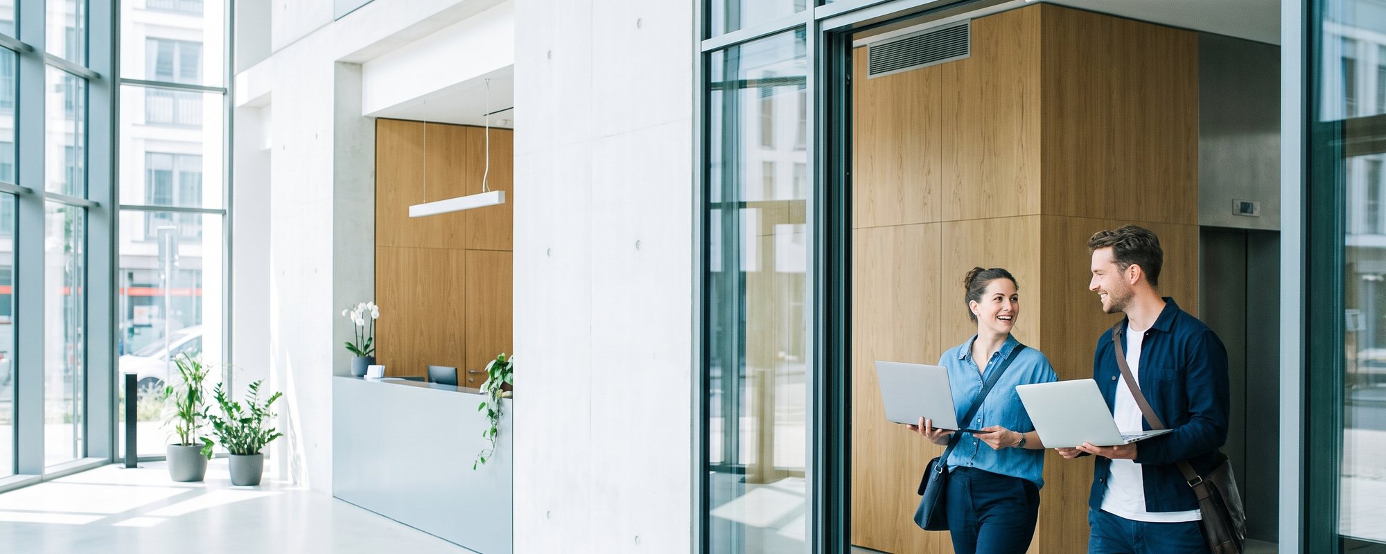 Mitarbeitende betreten das helle Büro eines Softwareunternehmens