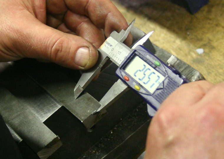 Hände messen ein Metallteil mit einem digitalen Messschieber – Motiv zu messbarer Produktdatenqualität