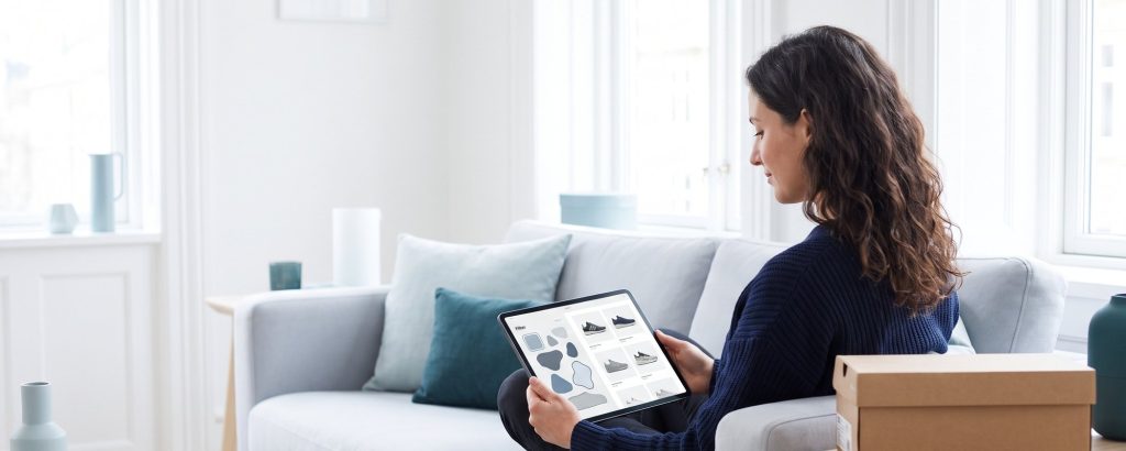 Frau filtert im Onlineshop auf dem Tablet Sneaker nach Farbe und Größe