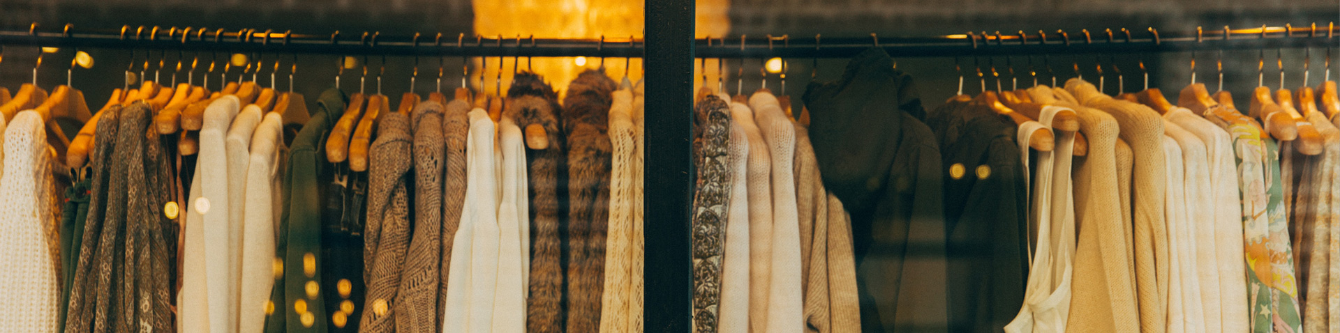 Kleiderstangen mit Strickjacken und Pullovern hinter einem Schaufenster – Popken Fashion Group Success Story