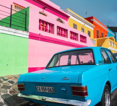blaues Auto vor buntem Haus
