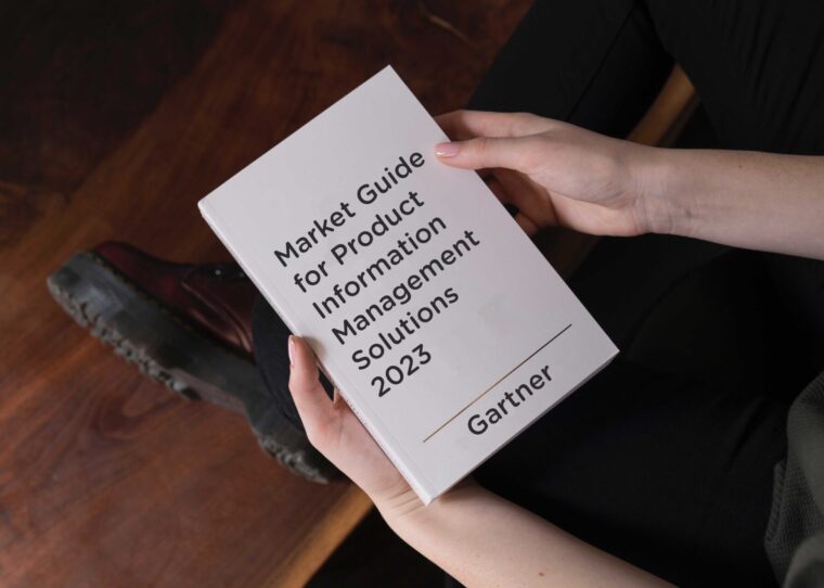 Jemand, der ein Buch mit dem Titel "Market Guide for Product Information Management Solutions 2023" von Gartner in der Hand hält