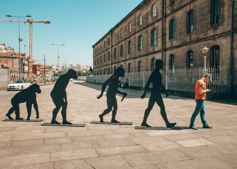 Mann auf einer Straße und vier Statuen hinter ihm als Darstellung der Evolution