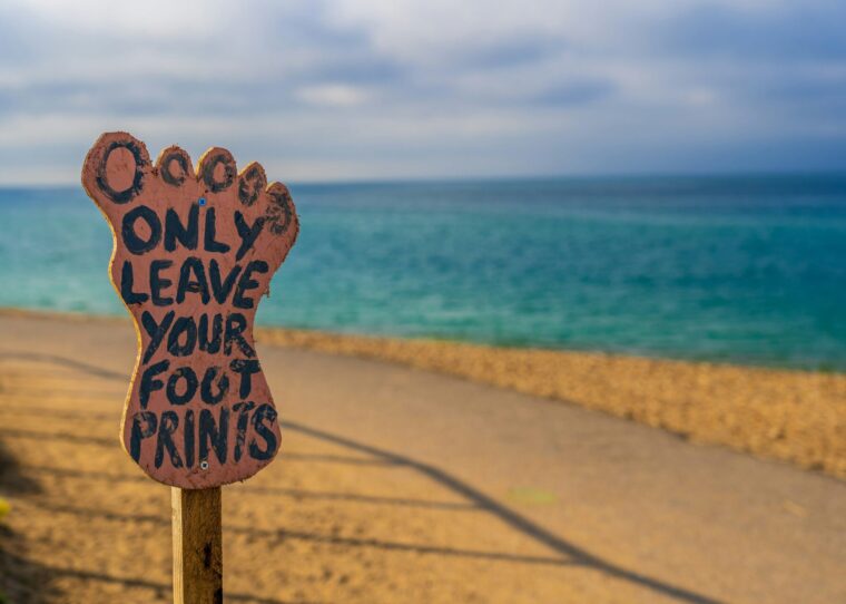 Strand mit einem Schild auf dem steht: Only leave your foot prints
