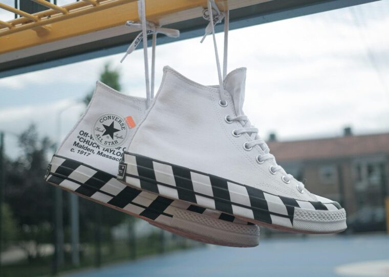 Weiße Converse-Schuhe, die an einem Gitter hängen