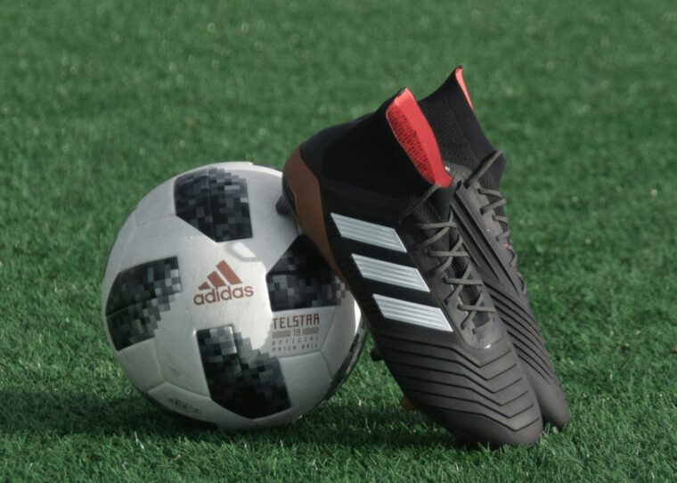 Ein Fußball und Fußballschuhe auf einem Rasen