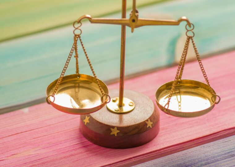 a gold balance scale on a colorful surface