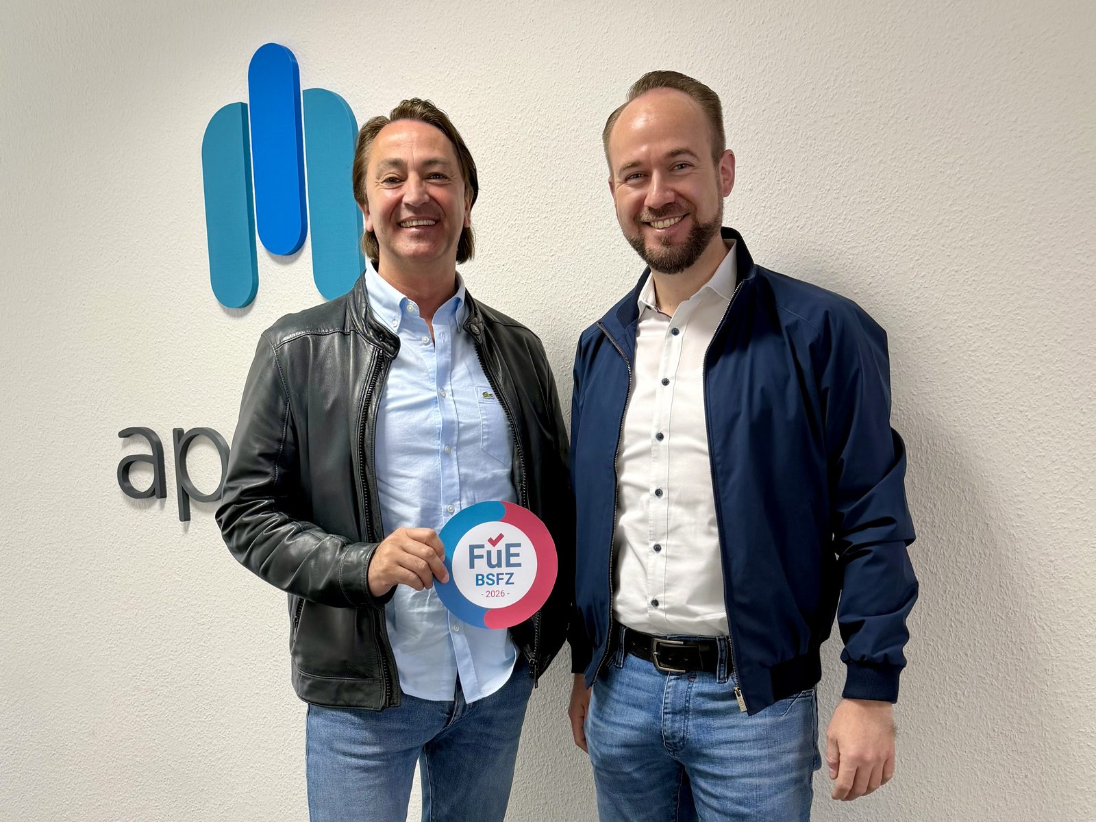 Norbert Weckerle und Tobias Marks von apollon halten die BSFZ-FuE-Plakette 2026 vor dem apollon-Logo.