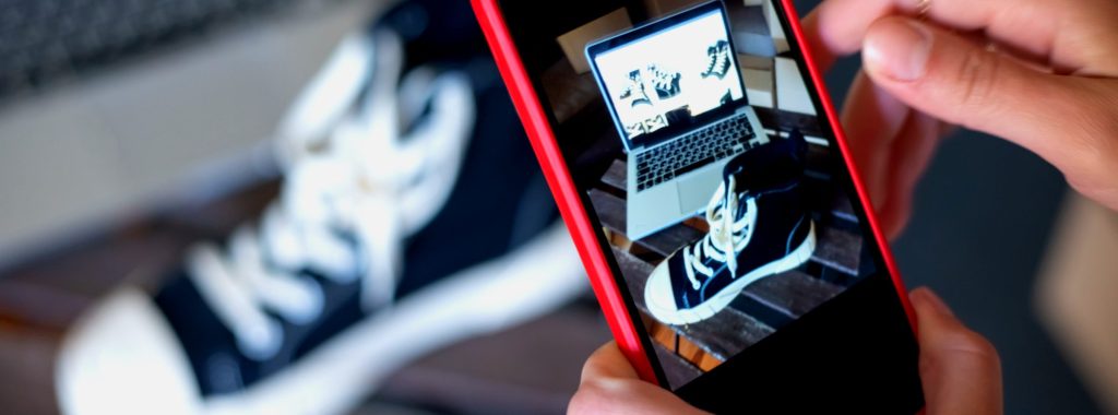 Hands photographing a sneaker with a smartphone — visual for managing product data for an online shop