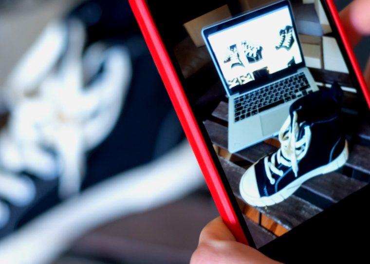 Hands photographing a sneaker with a smartphone — visual for managing product data for an online shop